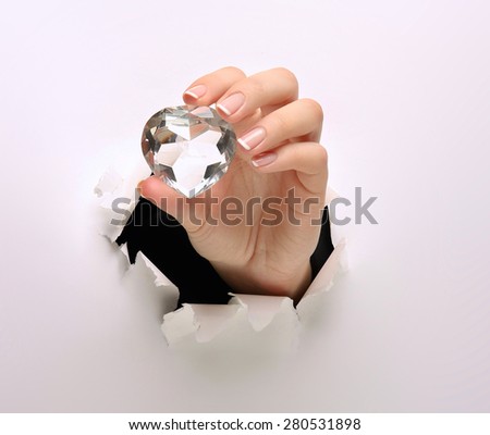 A female hand with a diamond, tearing white paper