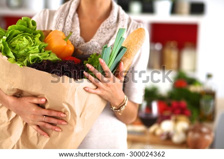 Young woman holding grocery shopping bag with vegetables Standing in the kitchen