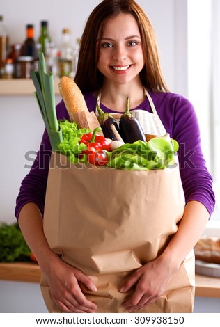Young woman holding grocery shopping bag with vegetables Standing in the kitchen