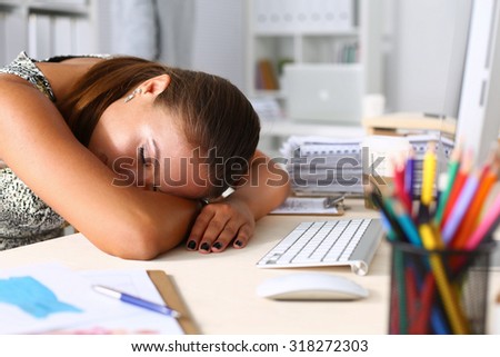 An exhausted businesswoman passed out at her desk .