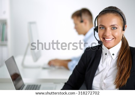 Portrait of a pretty call centre employee smiling at you while wearing her headset.
