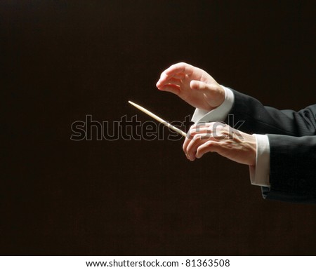 Concert conductor\'s hands with a baton isolated on a black background