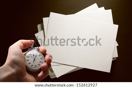 Paper cards on black and hand with stopwatch