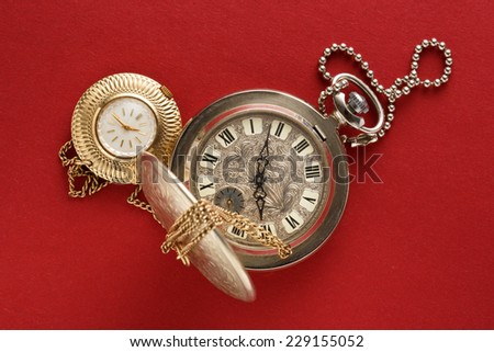 Two pocket watches with chain on red