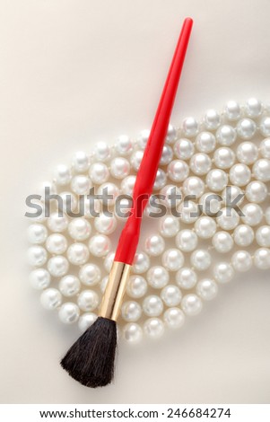 Make up brush over white pearl necklace