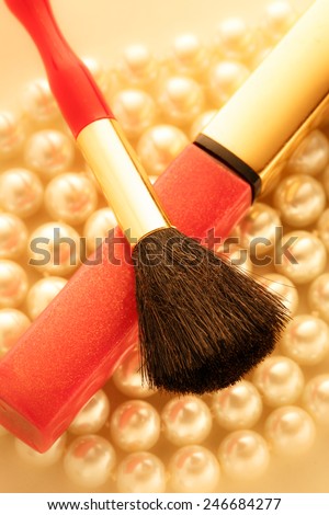 Make up brush and lipstick over white pearl necklace