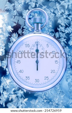 Stopwatch on winter window ice frozen background