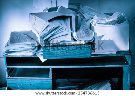 Messy workplace with table and stack of paper