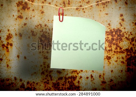 Blank green sticker and red clip on rusty surface