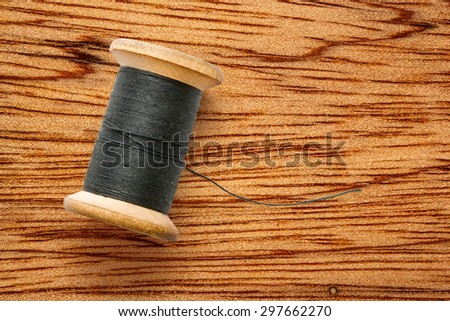 Wooden bobbin of black thread in closeup