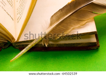 Opened book with feather isolated on green