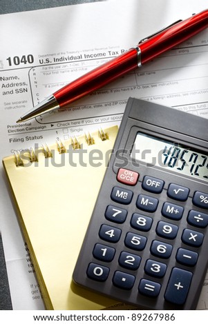 Tax form, red pen, notepad and calculator