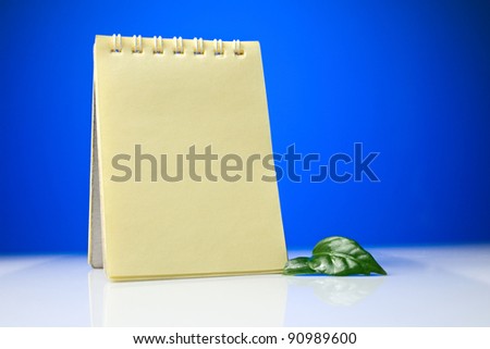 Notepad with green leaves on a blue-and-white background