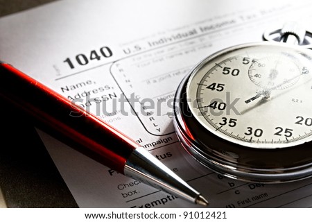 Tax form, red pen and stopwatch