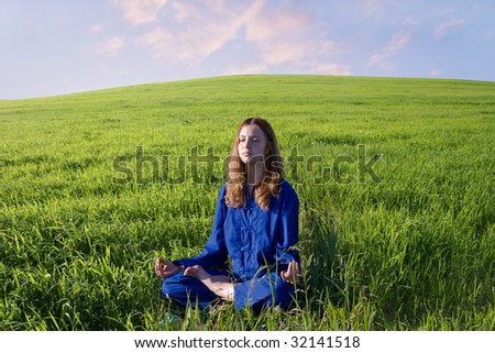 The girl is fond of Oriental Culture and meditates on the meadow.