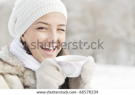 high key head portrait of laughing young woman, holding cup of hot drink, outdoor, winter