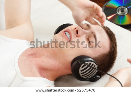 boy adores his favorite music  - headphones on and colorful CD on a background - focus on eyes