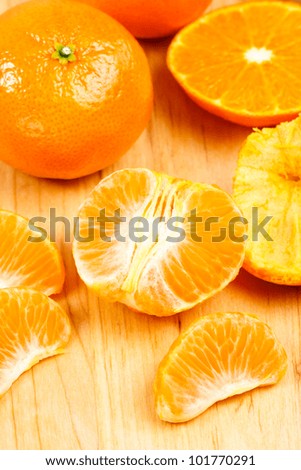Fresh, juicy mandarin oranges shown on a wood cutting board with whole orange and peeled sections