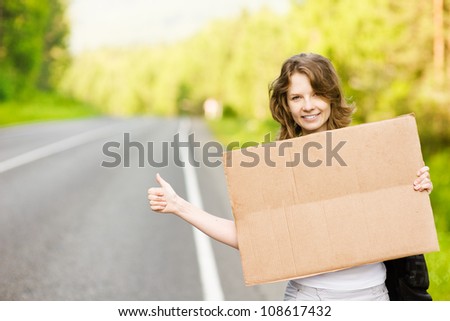 girl on the road waiting for a car with cardboard