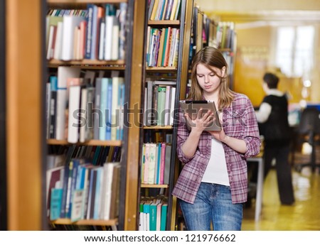 Young focused student using a tablet computer in a library