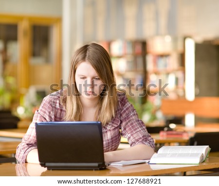 female student with laptop working in library.