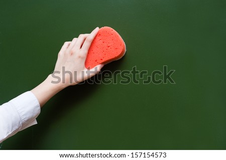 hand wipes the chalkboard, with a sponge