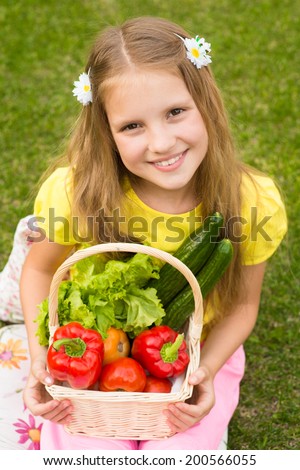 Harvests of vegetables - smiling girl with basket of vegetables in hands