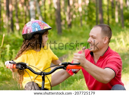father praises his daughter, who learned to ride a bike