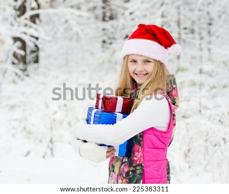 young girl with santa hat holding pile of gifts