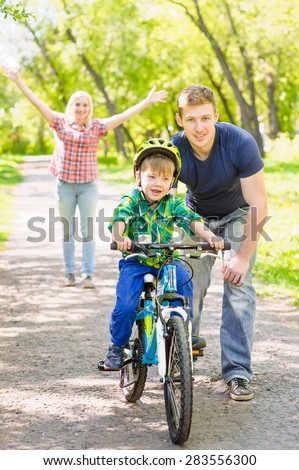 mother and father teaches his son to ride a bike