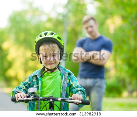 child on a bicycle with father in the park