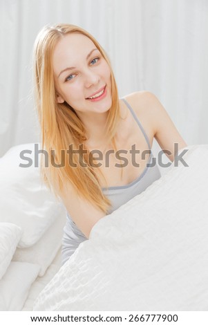 Smile of young Caucasian woman on the bed