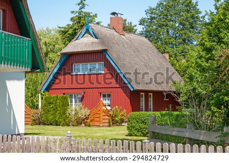 red painted wooden thatched-roof house with garden