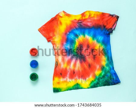 T-shirt painted in the style of tai Dai on a light pastel background. White clothes painted by hand. Flat lay. Place for text.