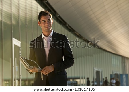 Elegant young businessman using his PC tablet while walking