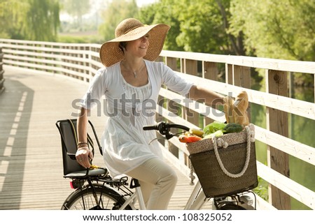 Woman cicyling with vegetables on her basket
