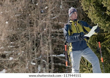 Young man looking at map, while walking with snow shoes