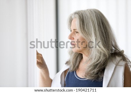 Portrait of senior woman looking outside the window