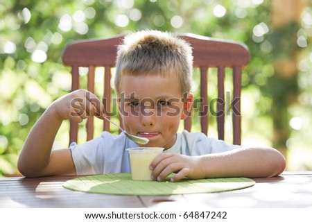 Cute little boy eating pudding outside
