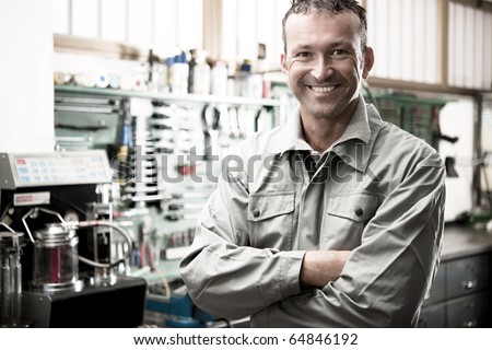 Close-up of a smiling mechanic inside his auto repair shop