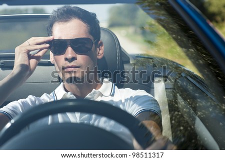 Front view of a young man driving his convertible car
