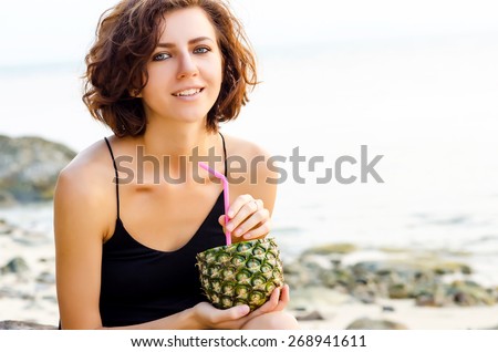 Woman drinks a cocktail from fresh pineapple