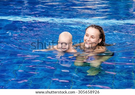 Mom teaches the child to swim  in the swimming pool