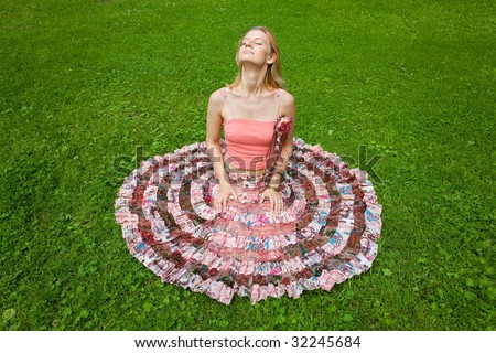 Girl with closed eyes sits on a grass and turns towards the sun