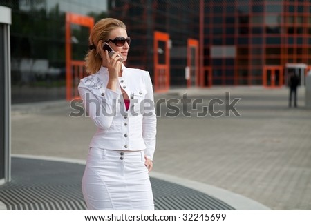 Young woman in a white suit speaks over the phone