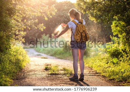 Woman is applying insect repellent against mosquito and tick on her hand during hike in nature. Skin protection against insect bite