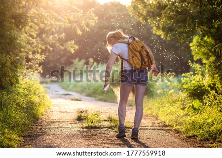 Woman applying insect repellent against mosquito and tick on her leg during hike in nature. Skin protection against insect bite