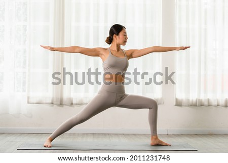 Similar – Image, Stock Photo Calm woman in Warrior pose on yoga mat