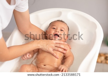 Calm of asian newborn baby bathing in bathtub.mother bathing her son in warm water.Happy adorable newborn infant smile in tub relax and comfortable.Newborn baby care concept 商業照片 © 