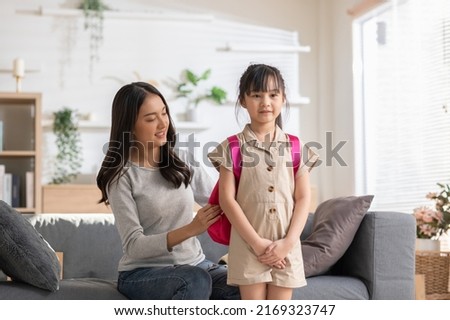Asian mother preparing school bag of her daughter ready to school in morning. Happy mom helping her little girl get ready for school with love. First day to school. Good moment family. ストックフォト © 